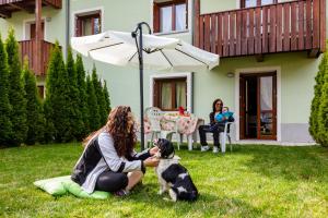 a woman sitting on the grass with a dog at Residence Rta La Rosa delle Dolomiti in Carisolo