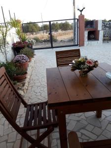 a wooden table and chairs with flowers on a patio at VILLETTA gelsomino E jasmin bifamigliare in Corsano