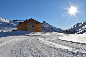 a house on a snow covered mountain with the sun w obiekcie apart-wolf-arlberg w mieście Warth am Arlberg