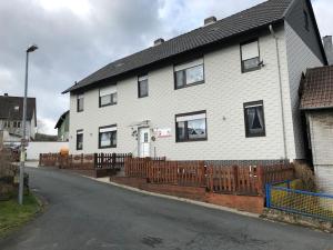 ein weißes Haus mit einem Holzzaun davor in der Unterkunft Ferienwohnung im Harz Wohlfühltempel in Winzenburg