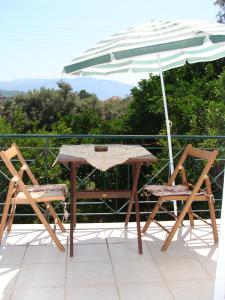 uma mesa e duas cadeiras e um guarda-sol numa varanda em Villa Galini em Nikiana