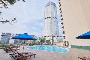 uma piscina com bancos e guarda-sóis e um edifício em The Galadari Hotel em Colombo
