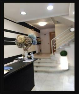 un vestíbulo con una escalera y un jarrón de flores en Hotel Fuente La Plata, en Oviedo