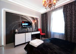 a bedroom with a bed and a television and a chandelier at Partner Guest House Velyka Vasylkivska in Kyiv