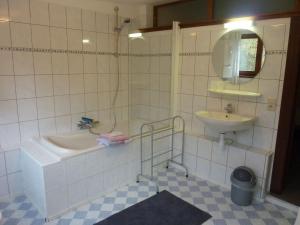 a white tiled bathroom with a sink and a tub and a mirror at Boutique Pet friendly Apartment in Bohon in Barvaux