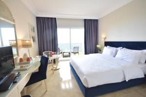 a bedroom with a bed and a desk with a television at Ramada Plaza by Wyndham Tunis in Gammarth