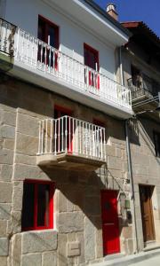 einen Balkon an der Seite eines Gebäudes mit roten Fenstern in der Unterkunft Casa Choupas in Cangas