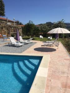 a swimming pool with lounge chairs and an umbrella at Quinta das Aranhas in Castelo de Paiva