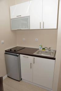 a kitchen with white cabinets and a sink at Apartments Mianiko in Herceg-Novi