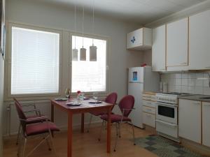 una cocina con mesa y sillas y una cocina con armarios blancos. en Mini-Mani Northern House, en Sorsakoski