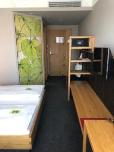 a room with two beds and a tv and a shelf at Hotel Linde in Günzburg