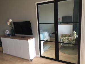 a room with a mirror and a tv and a chair at Zeesterflat 117 in Egmond aan Zee