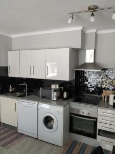 a kitchen with white cabinets and a washing machine at Apartamento Markinca in Vilamoura