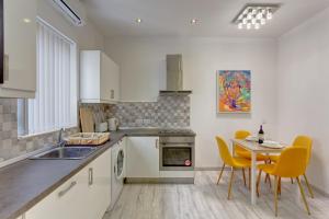una cucina con tavolo, sedie gialle e lavandino di Cozy Apartment in an Amazing Location a Sliema
