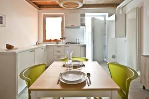 a kitchen with a wooden table and green chairs at GuestHost - Casa Caramelli in Cernusco sul Naviglio