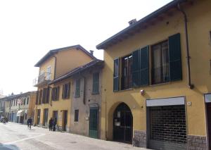 ein gelbes Gebäude mit grünen Rollläden auf einer Straße in der Unterkunft CaseOspitali - CASA CARAMELLI bilocale in corte storica in Cernusco sul Naviglio