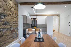eine Küche und ein Esszimmer mit einem Holztisch und einer Steinmauer in der Unterkunft Cantabric Plaza / Iberorent Apartments in San Sebastián