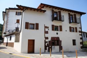 un edificio blanco con ventanas con persianas marrones en Hostal Ameztia, en Doneztebe