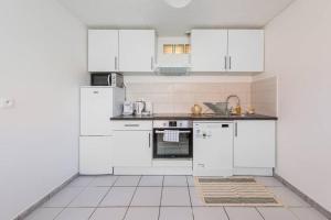 a white kitchen with white appliances and a tiled floor at Grand T2 50m2 - 10min Paris Orly - Jacuzzi - Fan in Alfortville