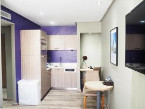 cocina con paredes de color púrpura, mesa, mesa y sillas en Le 22 Appart'Hotel, en Casablanca