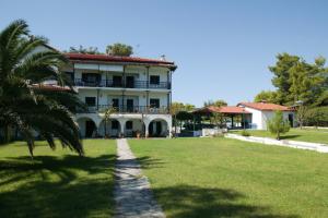 a large white building with a palm tree in the foreground at Lagonisi Beach Resort in Ormos Panagias