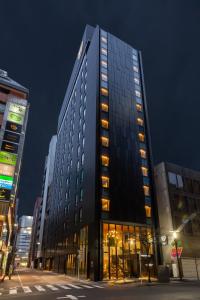 un edificio alto y negro con muchas ventanas por la noche en The Royal Park Canvas - Ginza 8 en Tokio