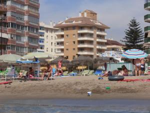 Grupa ludzi na plaży z parasolami w obiekcie Apartamentos Mary w mieście Fuengirola