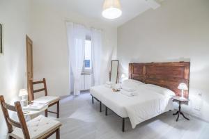 a white bedroom with a large bed and a chair at Pontormo by Mmega in Florence +19 photos