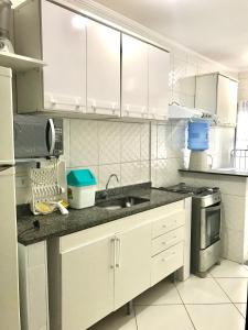 a kitchen with white cabinets and a sink at Condominio residencial Ubatuba in Ubatuba