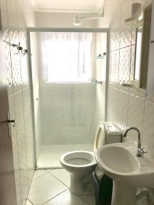Baño blanco con aseo y lavamanos en Condominio residencial Ubatuba, en Ubatuba