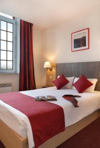 una habitación de hotel con una cama grande con almohadas rojas en Vacancéole - Les Demeures Champenoises Confort, en Épernay