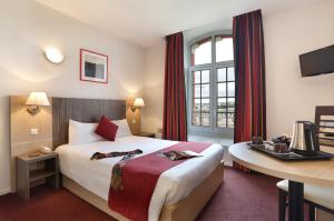 エペルネーにあるVacancéole - Les Demeures Champenoises Confortのベッド、デスク、窓が備わるホテルルームです。