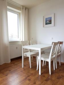 een witte tafel en stoelen in een kamer met een raam bij CHILLIapartamenty - LATARNIK in Kołobrzeg