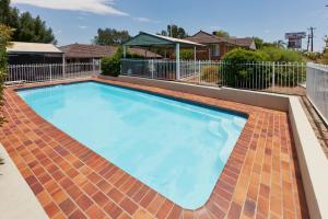 a large swimming pool with a brick floor and a fence at Abraham Lincoln Motel in Tamworth