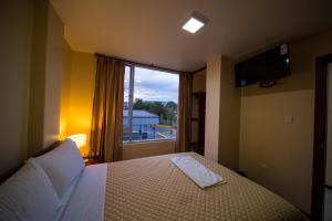 a bedroom with a bed and a large window at Hotel Sumak Pakari in Riobamba
