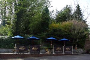 a group of blue umbrellas in a garden with a person sitting underneath at The Barleycorn Inn in Collingbourne Ducis