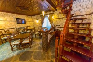 Heraklis Hotel في بيرات: غرفة طعام مع طاولة وكراسي وجدار حجري