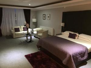 a hotel room with a bed, table, and a television at The Diplomat Hotel Restaurant & Spa in Llanelli