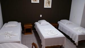 a room with three beds with white linens at HOTEL MAGIA DO MAR in Capão da Canoa