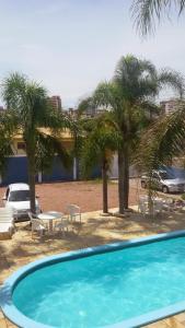 una piscina con una mesa y palmeras en HOTEL MAGIA DO MAR en Capão da Canoa