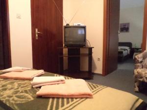 a room with a bed and a tv and towels at Hotel Le Village in Skopje