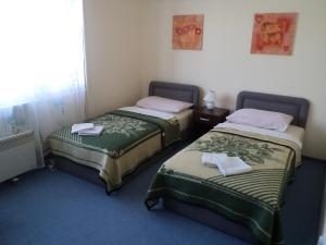 two beds in a hotel room with towels on them at Hotel Le Village in Skopje