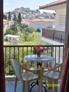 a table with two chairs and a vase with flowers on a balcony at Theoxenia Paralio Astros in Paralio Astros