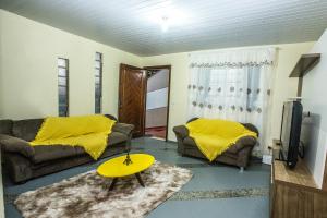 een woonkamer met 2 banken en een gele deken bij Casa Grande com 2 quartos e 1 suíte in Foz do Iguaçu