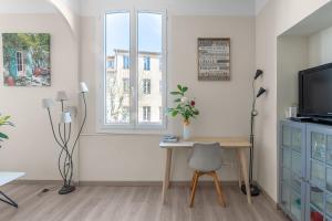 a living room with a desk and a tv and a window at My rima in Antibes