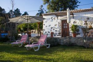 duas cadeiras e um guarda-sol em frente a uma casa em Quinta do Tempo Turismo Rural em Monchique