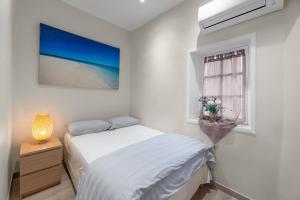 a white bedroom with a bed and a window at My rima in Antibes