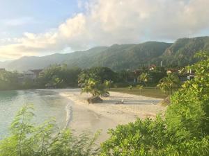 a beach with trees and mountains in the background at Eden Island Gem in Eden Island
