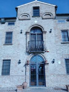 Edificio de ladrillo con ventana y balcón en Locanda Corte Arcangeli, en Ferrara