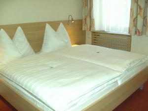 a large white bed with white sheets and pillows at Frühstückspension Leopold Janu in Senftenberg